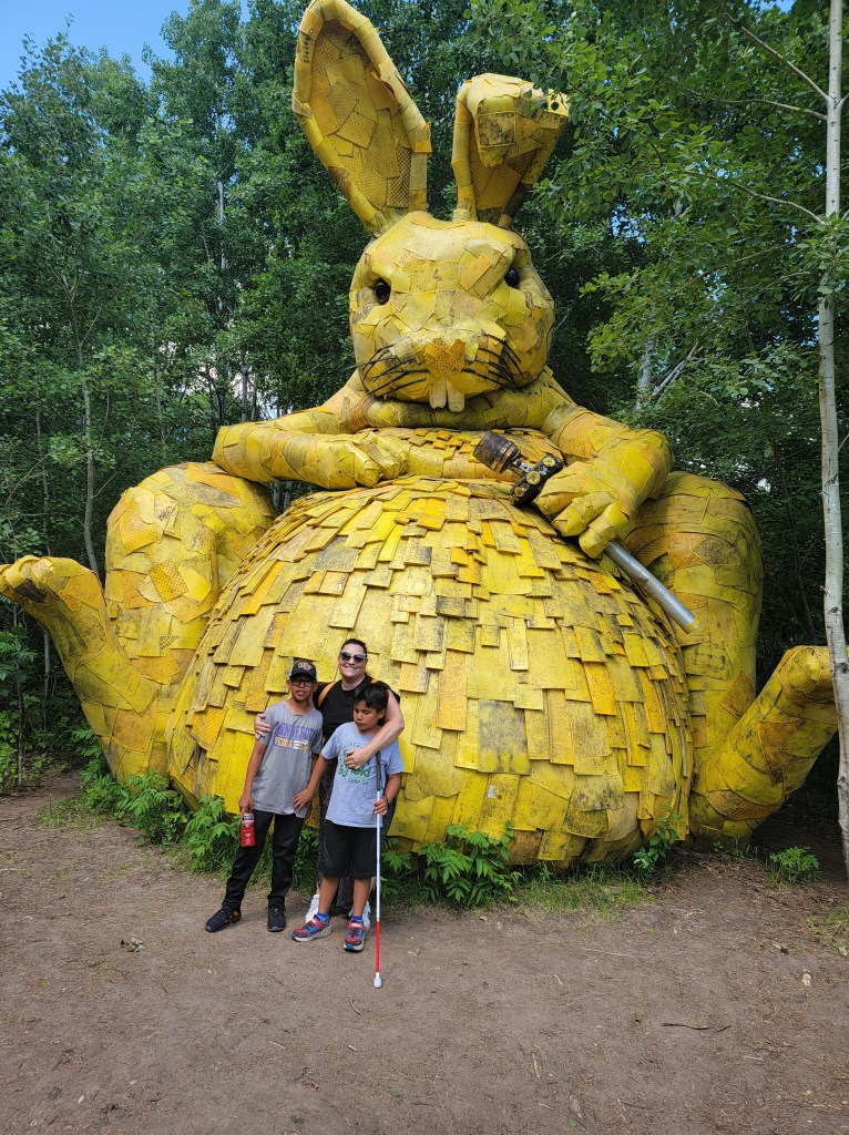 A mom and two boys pose in front of the golden rabbit.