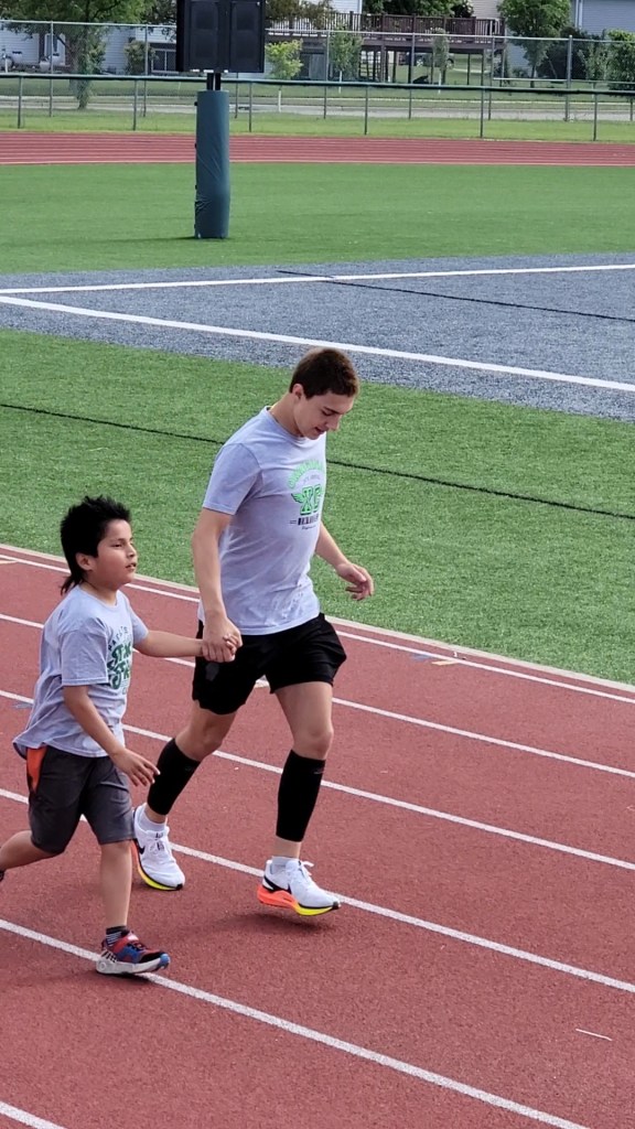 A young boy being guided on a track by an older boy.