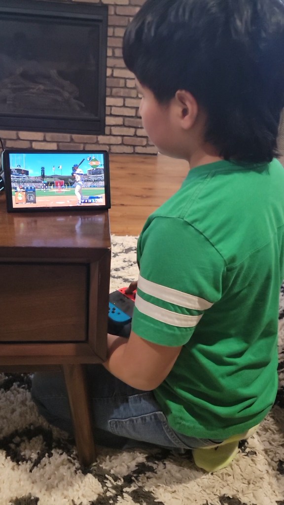 Boy sitting on the floor playing a video game. Leaning in and using the sounds to play. 
