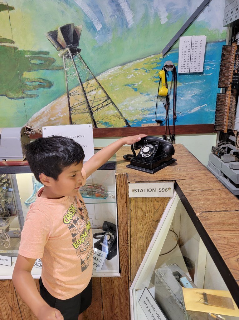 Little boy grabbing the receiver of a black rotary phone. 